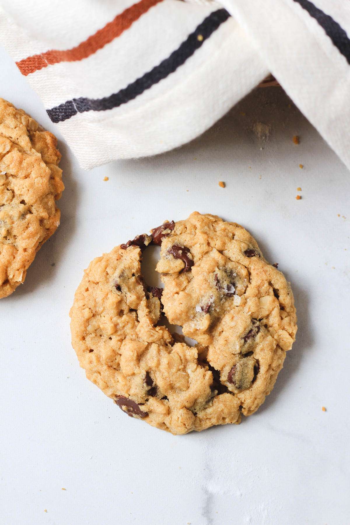 A peanut butter chocolate chip oatmeal cookie on a white counter.