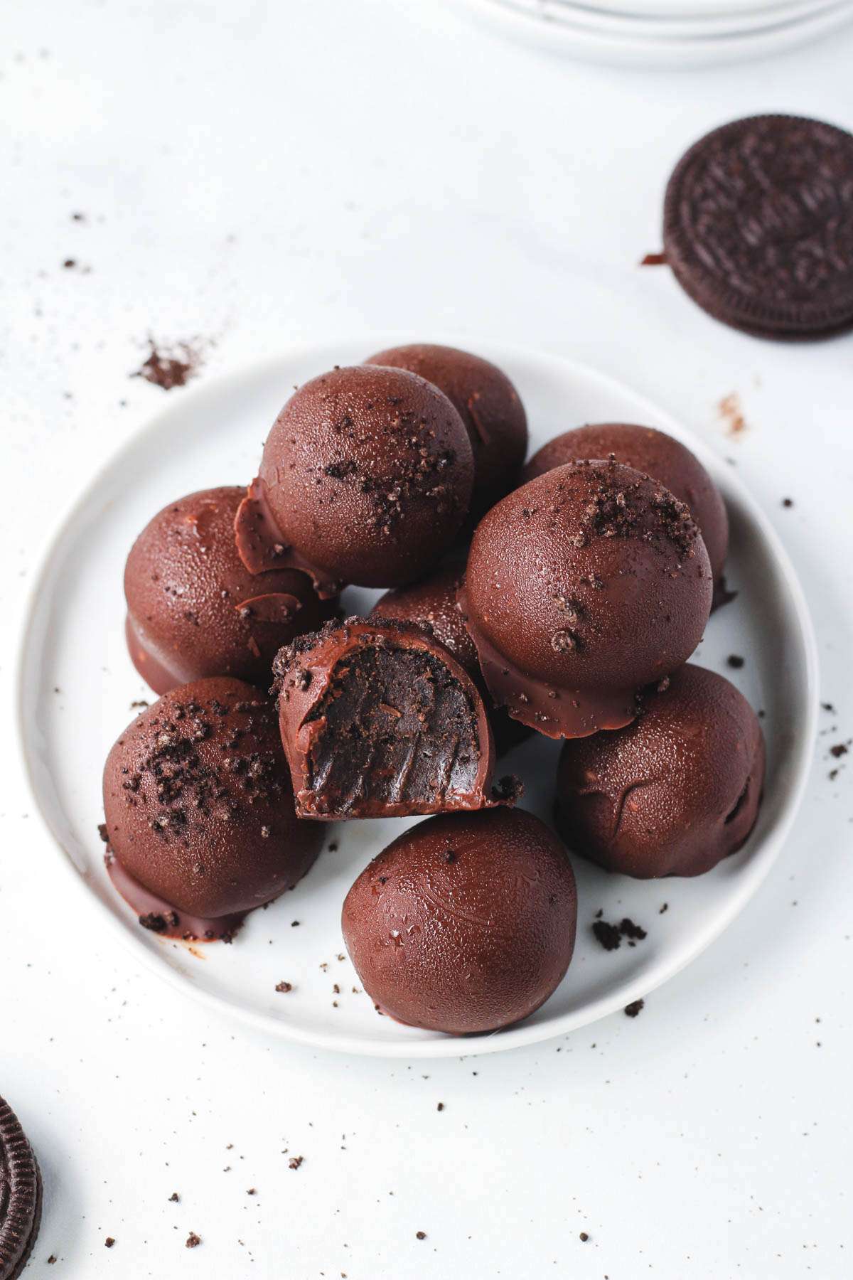 A small white plate filled with vegan truffle balls and one with a bite missing.