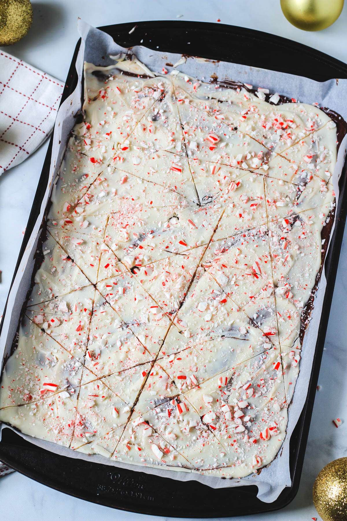 A rimmed baking sheet with vegan peppermint bark cut into pieces.
