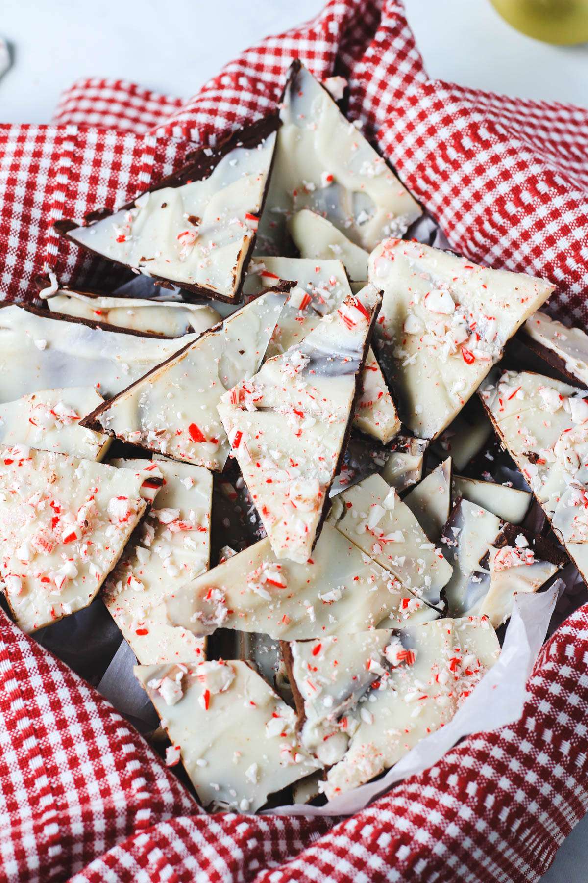 A red and white cloth lined basket filled with vegan peppermint bark pieces.