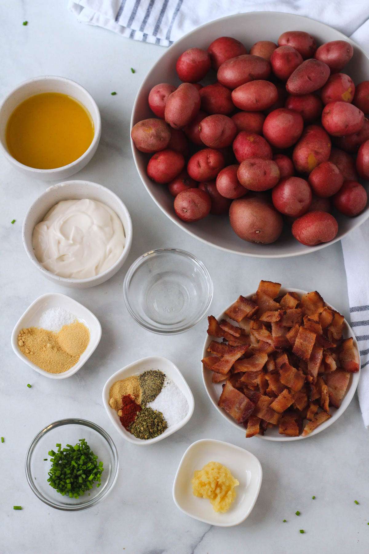Ingredients for breakfast smashed potatoes on a white counter with a blue and white towel.