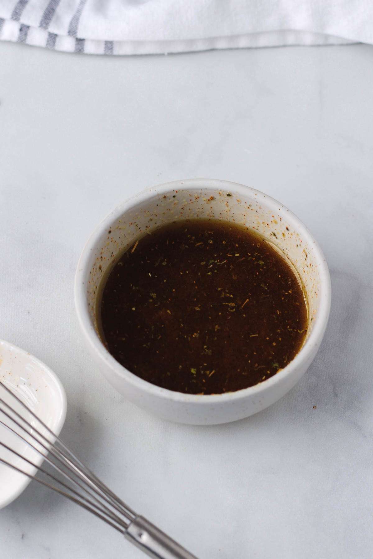 A white bowl with the olive oil mixture for breakfast smashed potatoes.
