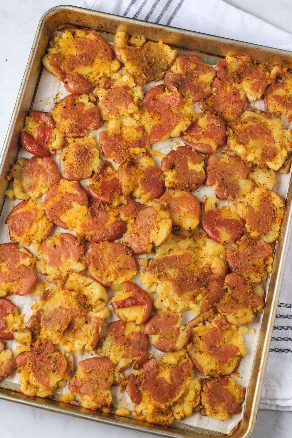 A rimmed baking sheet with smashed potatoes after roasting in the oven.