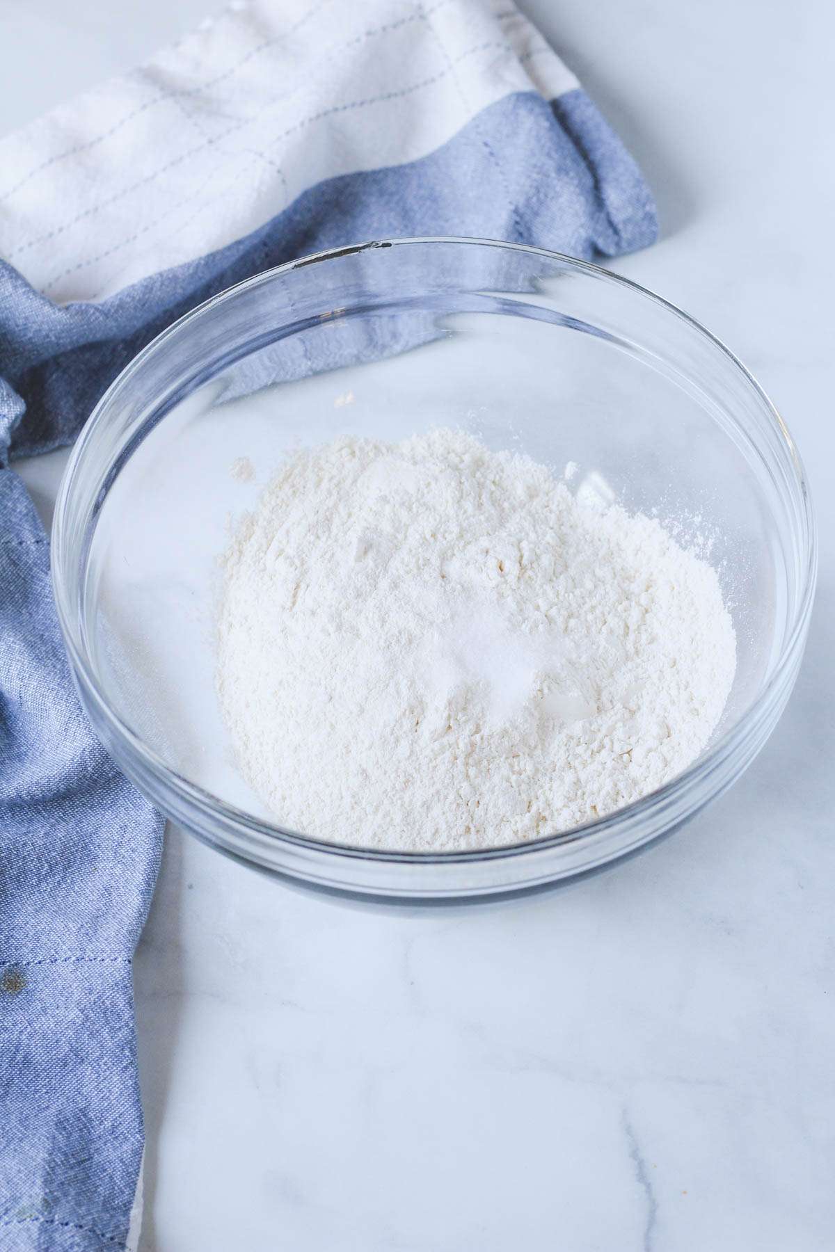 A glass bowl with flour and salt before mixing.