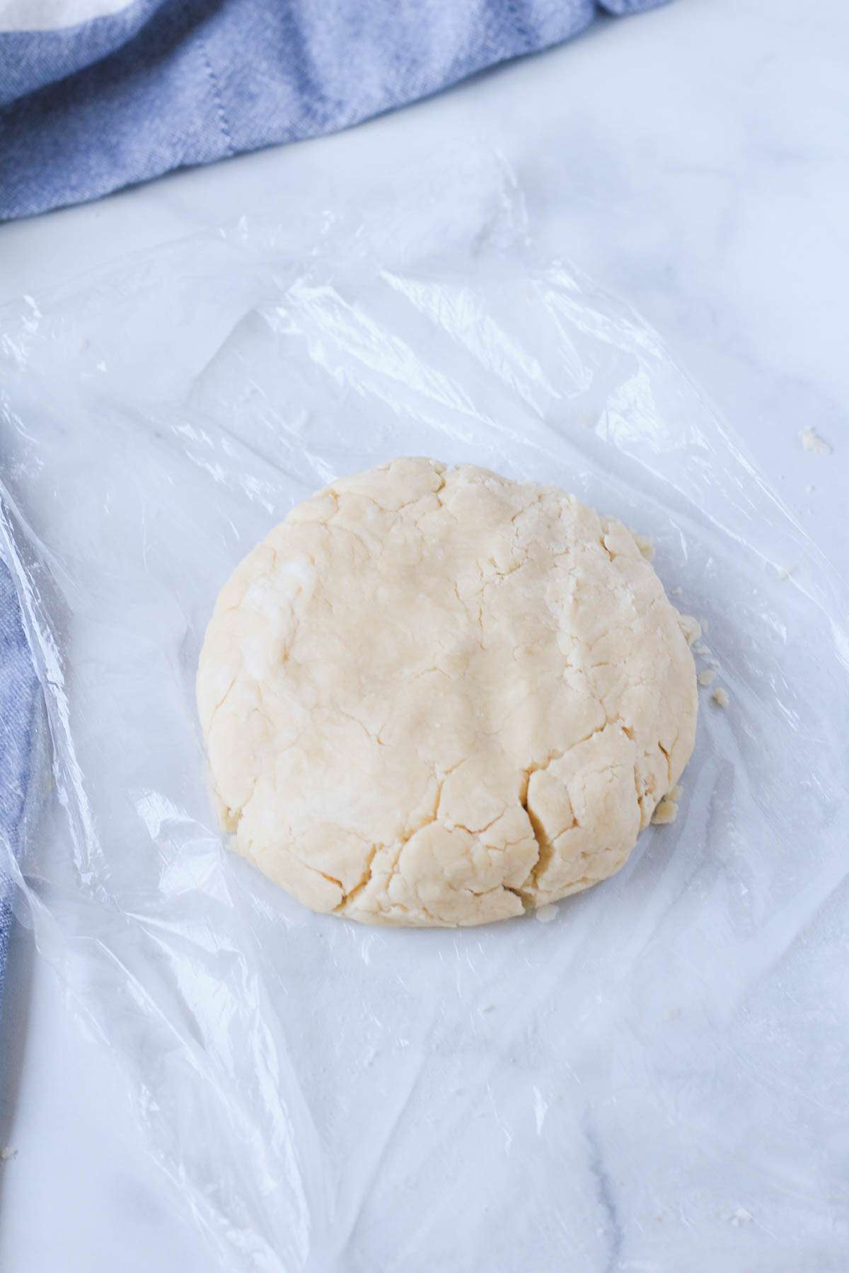 A round disk of dough on a piece of plastic wrap before chilling.