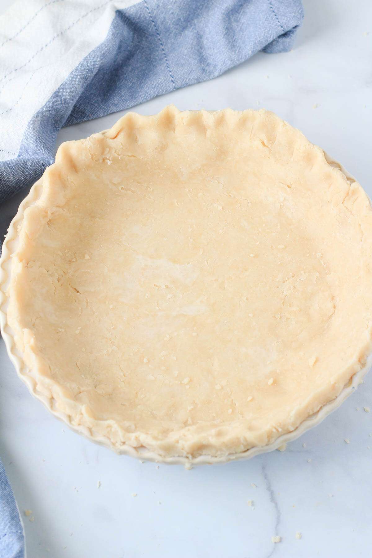 Crisco pie dough in a cream pie pan on a white counter.