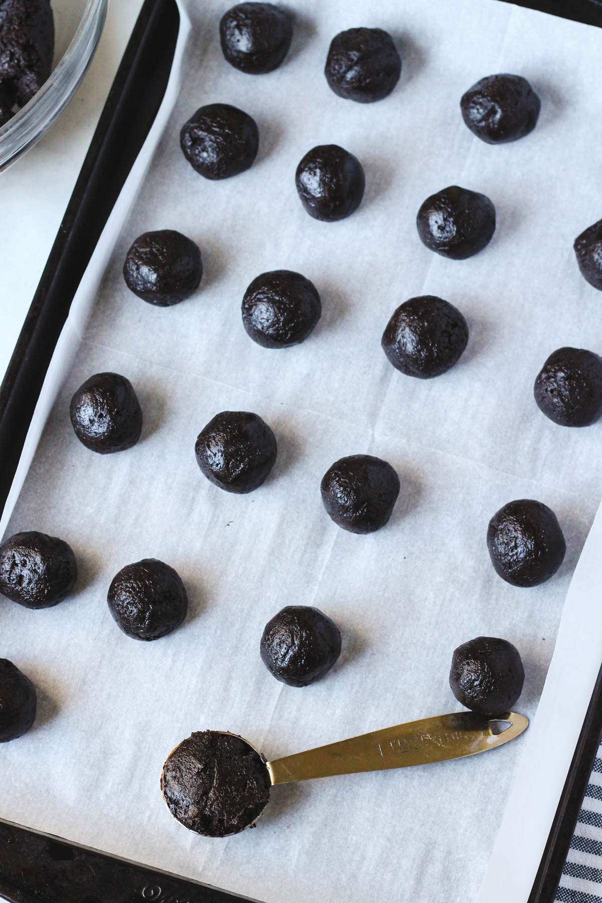 A parchment paper lined baking sheet with Oreo truffle balls before decorating.