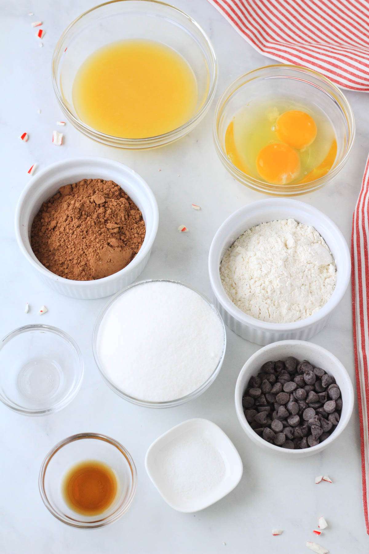 Ingredients for peppermint brownies on a white counter with a red and white dish towel to the right.