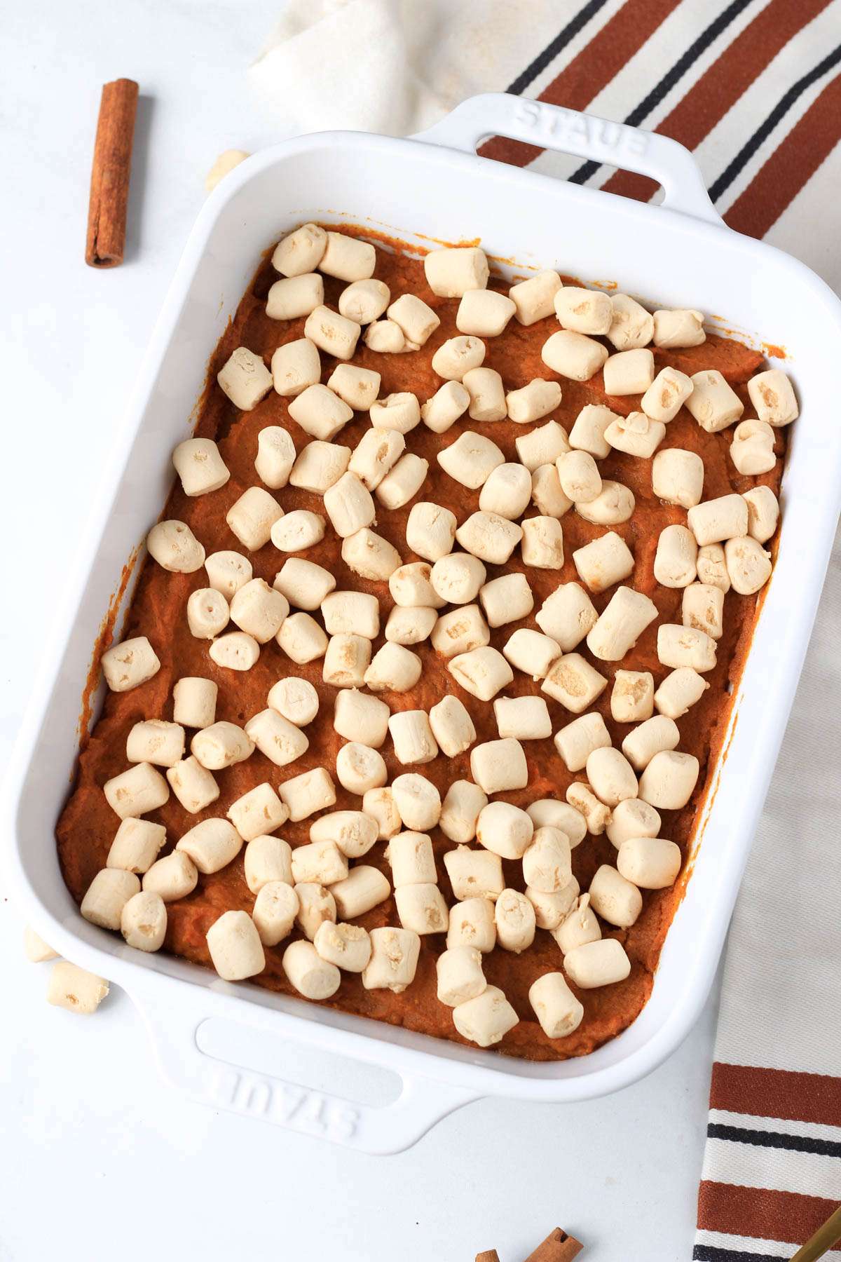 Baked vegan maple sweet potato casserole in a white baking dish on a white counter.