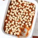 A close up of the casserole dish of maple sweet potato casserole missing a scoop in the bottom right corner.