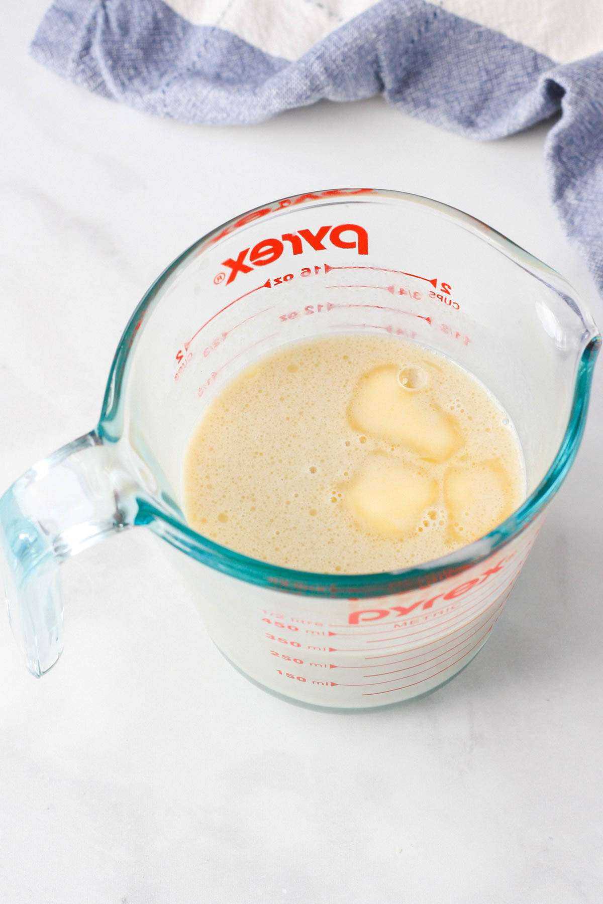 A liquid measuring cup with vegan butter and non-dairy milk.