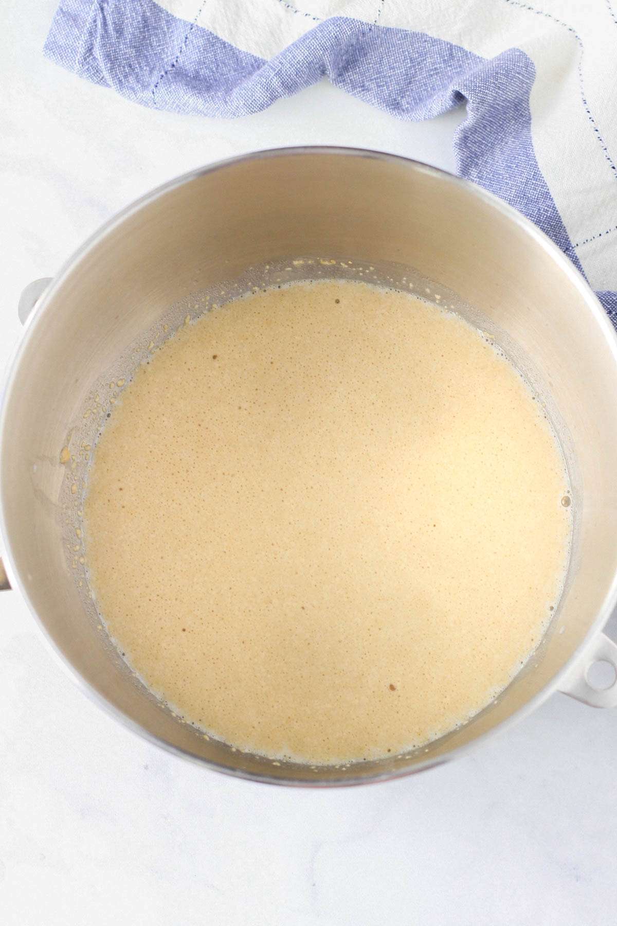 A silver mixing bowl with activated yeast.