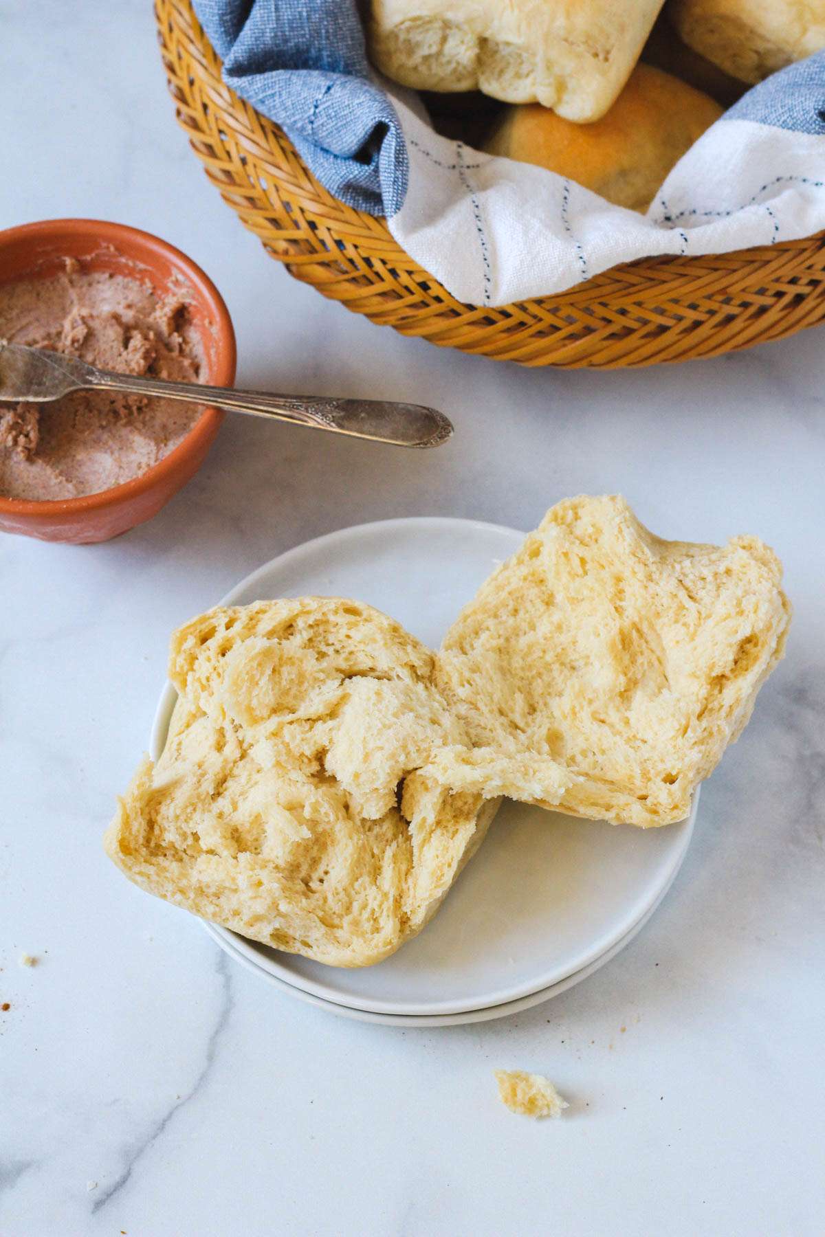 A small white plate with a sliced open dinner roll and a small bowl of cinnamon maple butter in the top left.