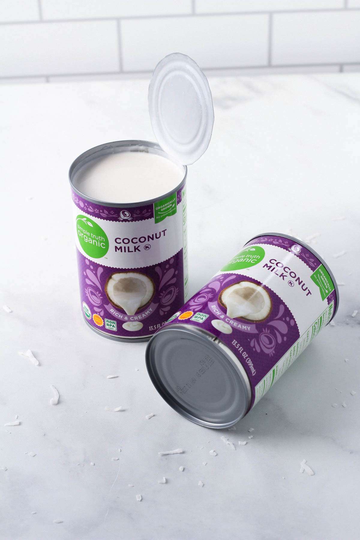 Two purple cans of coconut milk on a white counter.