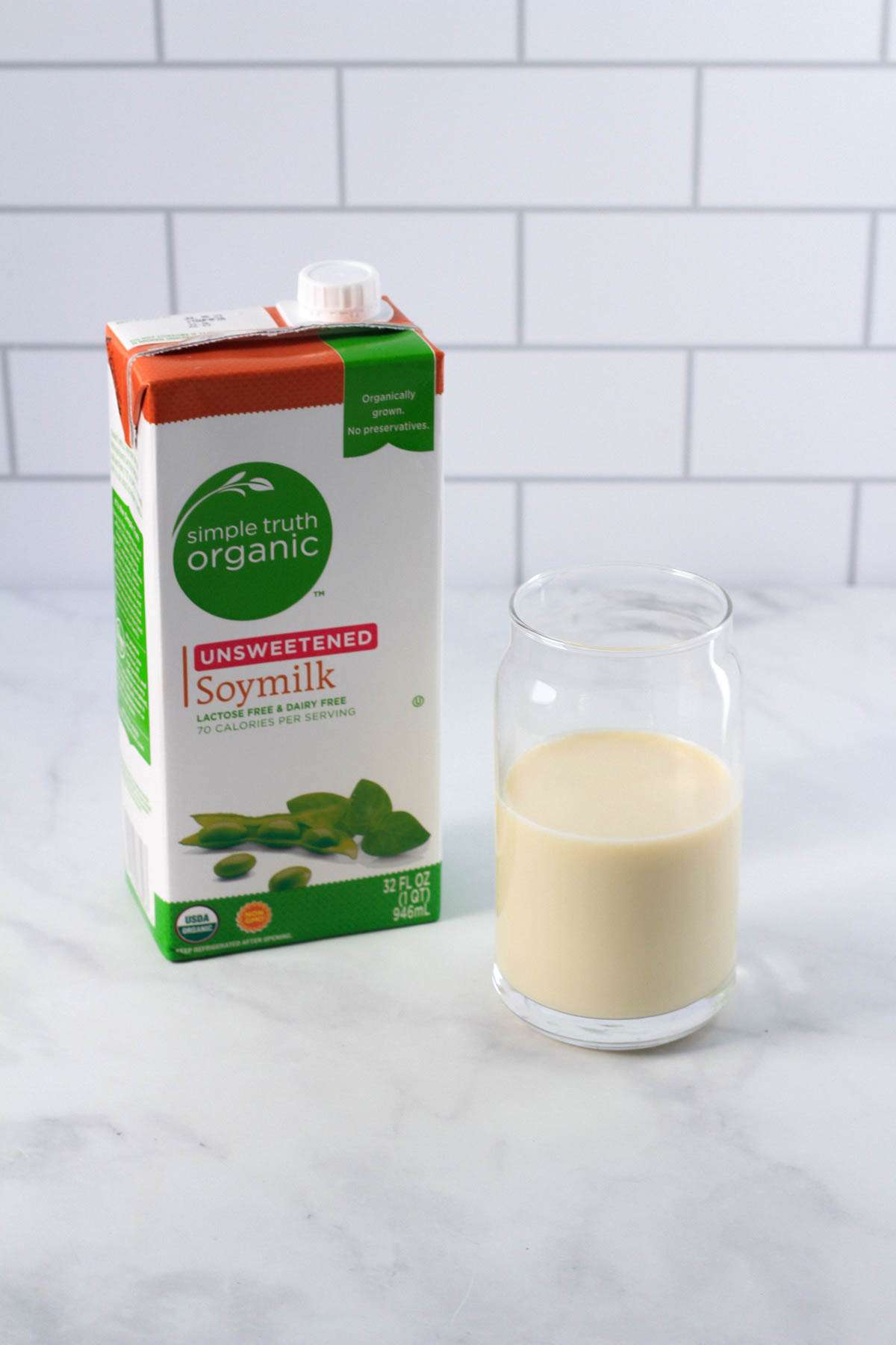 A box of soy milk on the left with a glass of soy milk on the right.