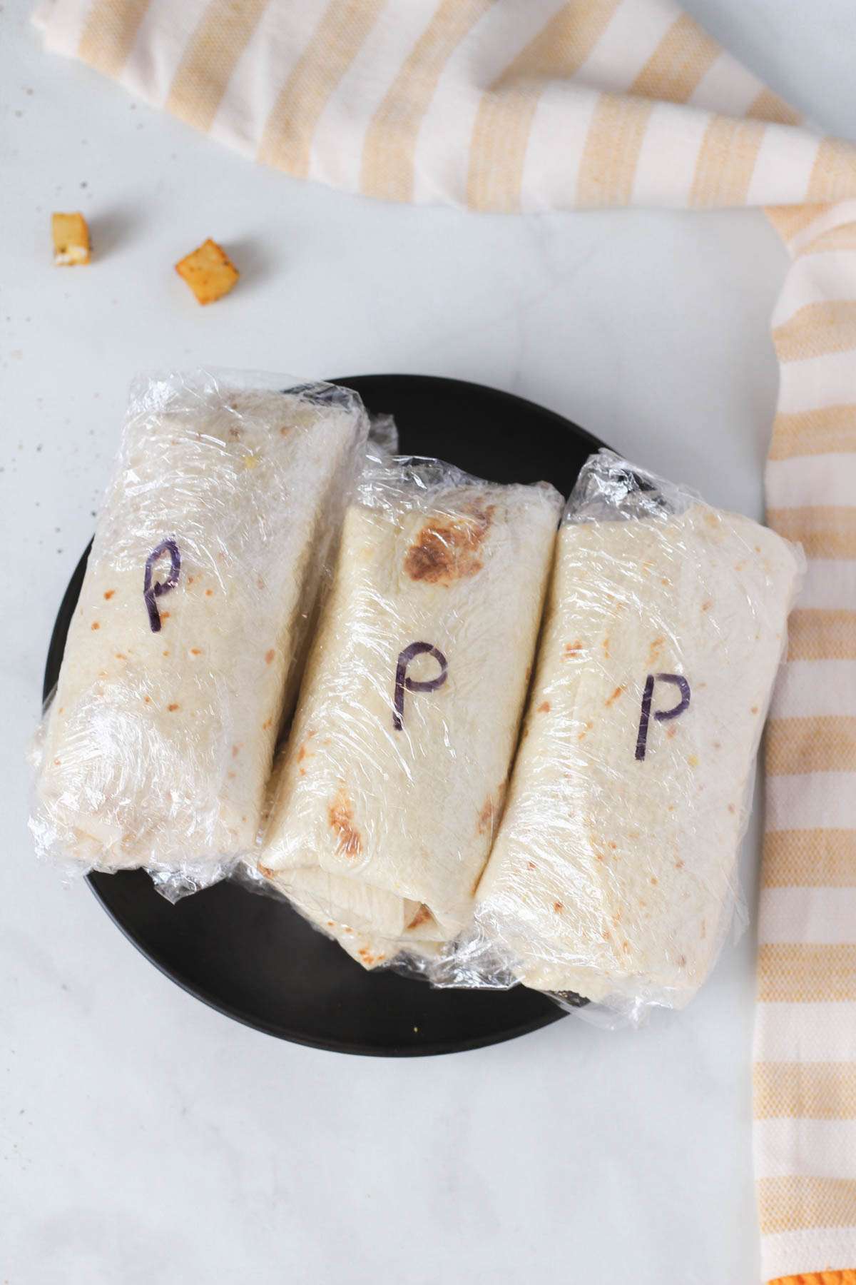 A black plate with freezer breakfast burritos labeled with a 'P' to indicate that they are potato and egg burritos.