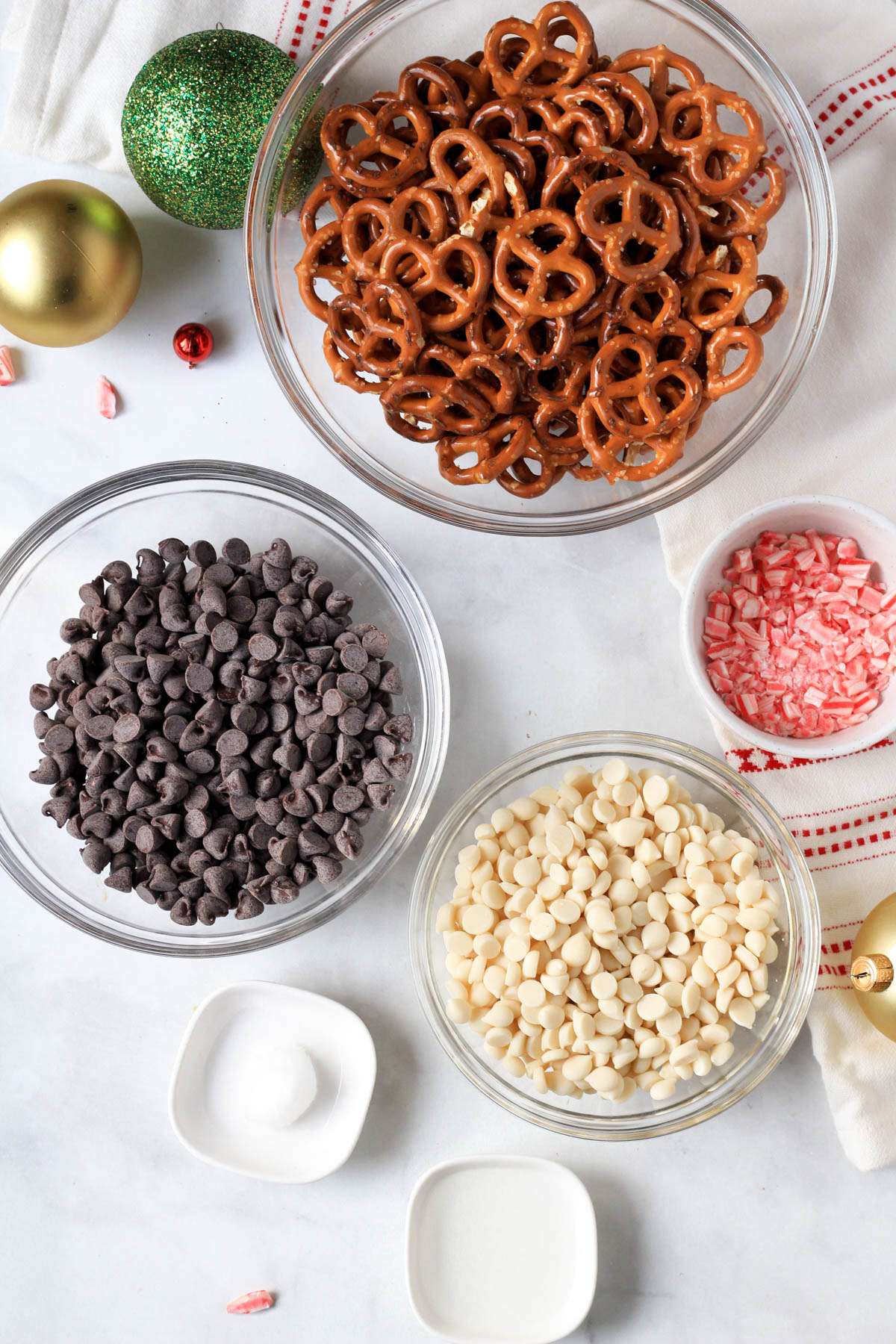 Ingredients for peppermint bark pretzels on a white counter.