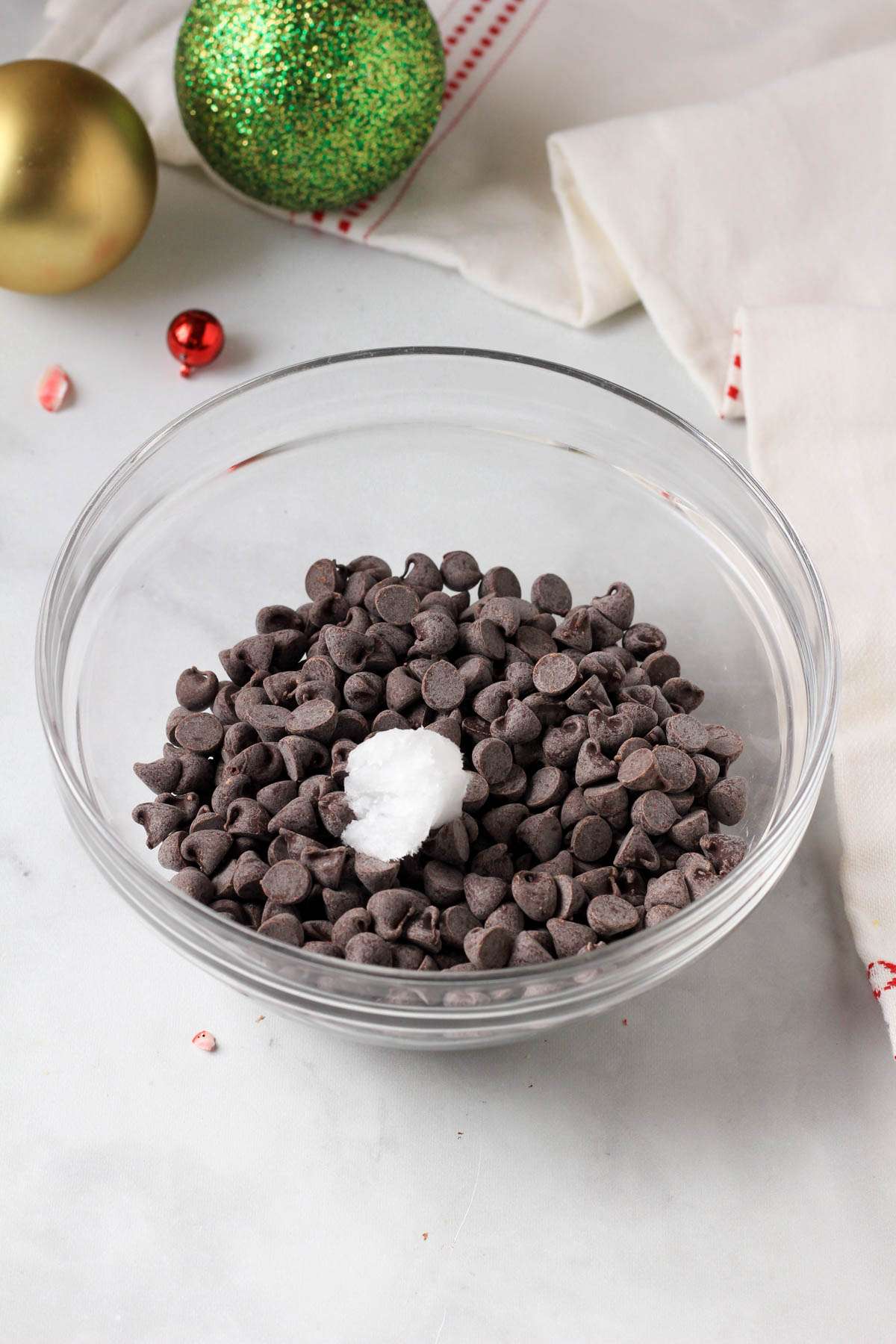 A glass bowl with dairy-free chocolate chips and coconut oil before melting.