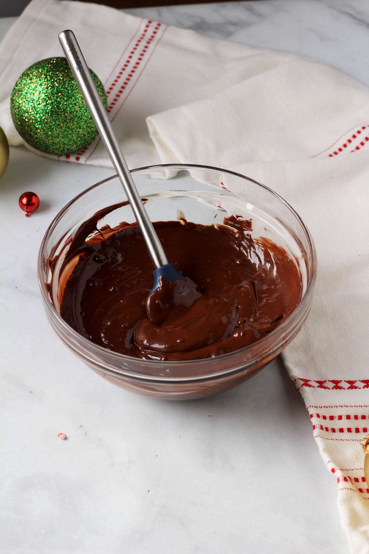 A glass bowl with melted dairy-free chocolate and a rubber spatula.