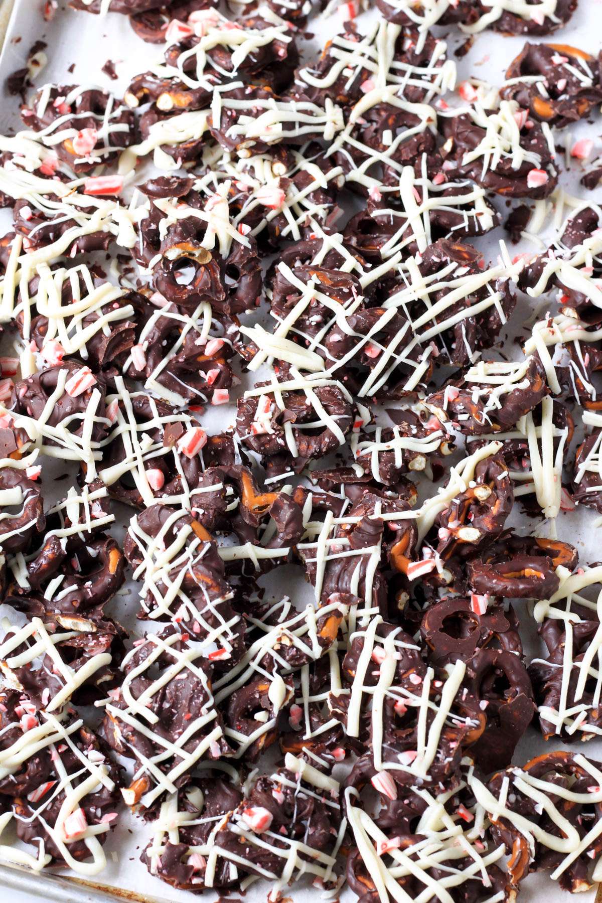 Broken pieces of peppermint bark pretzels on a parchment paper lined baking sheet.