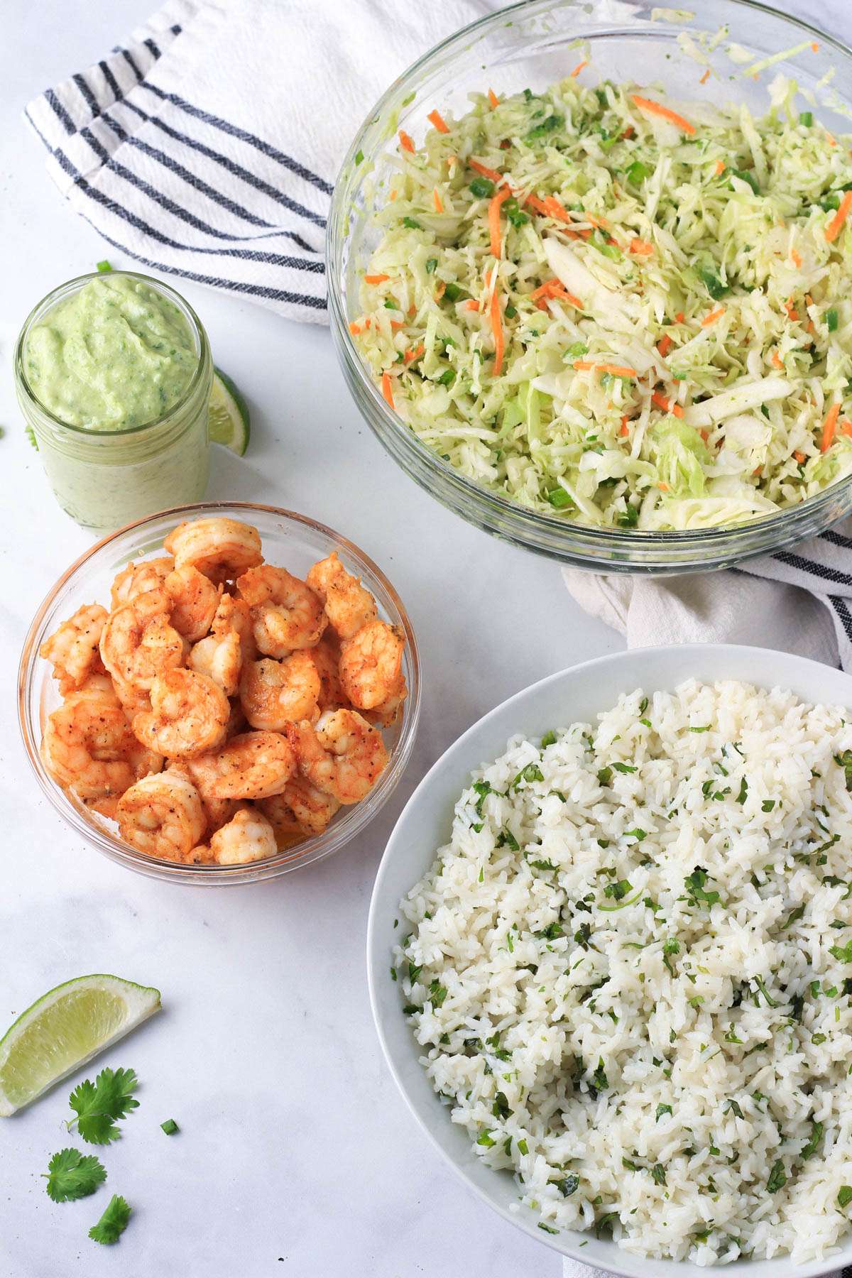 Ingredients for shrimp taco lunch bowls on a white counter.