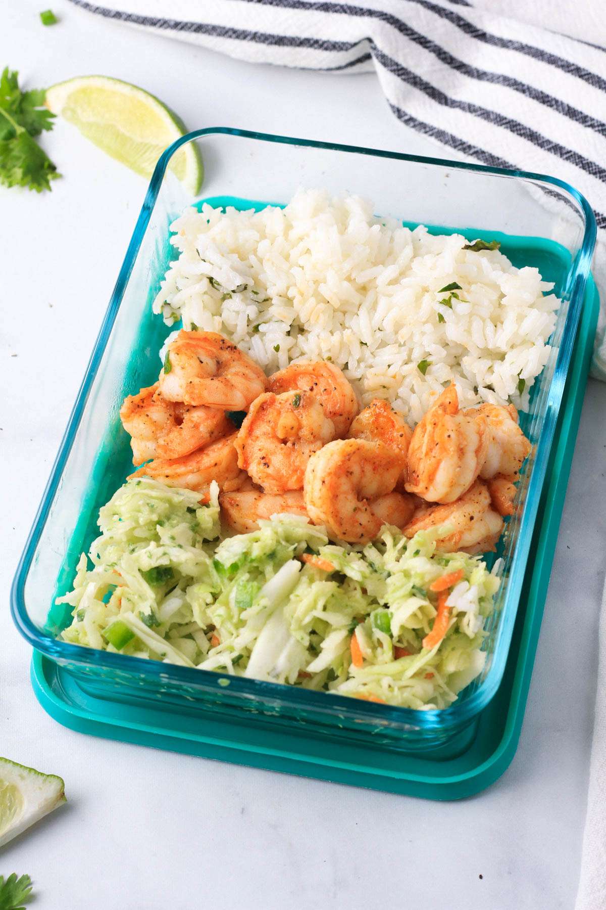 A glass meal prep container with shrimp taco lunch bowls served and ready to go.