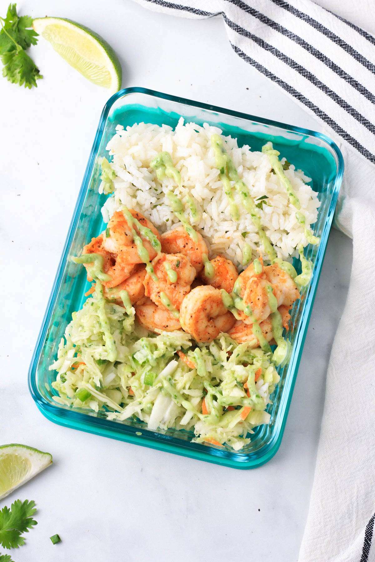 A top down photo of a glass pyrex with a serving of the shrimp taco lunch bowl on a white counter.