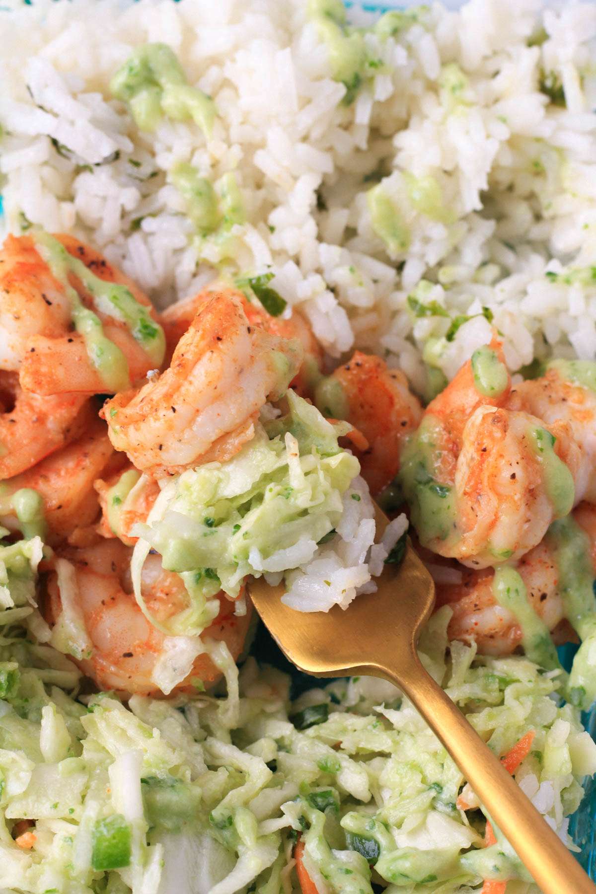 A gold fork with a bite of the shrimp taco lunch bowl on the prongs.