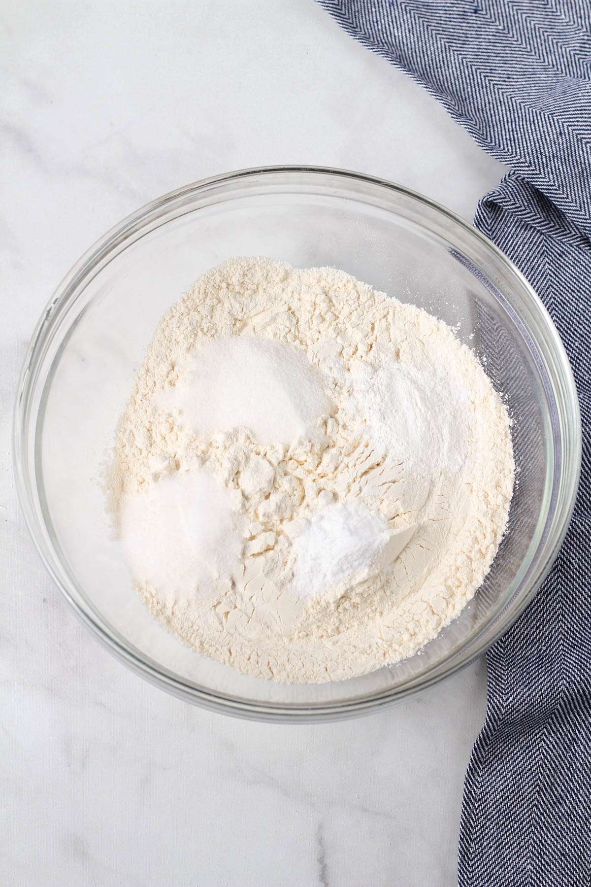 A glass bowl with the dry ingredients for biscuits before mixing.