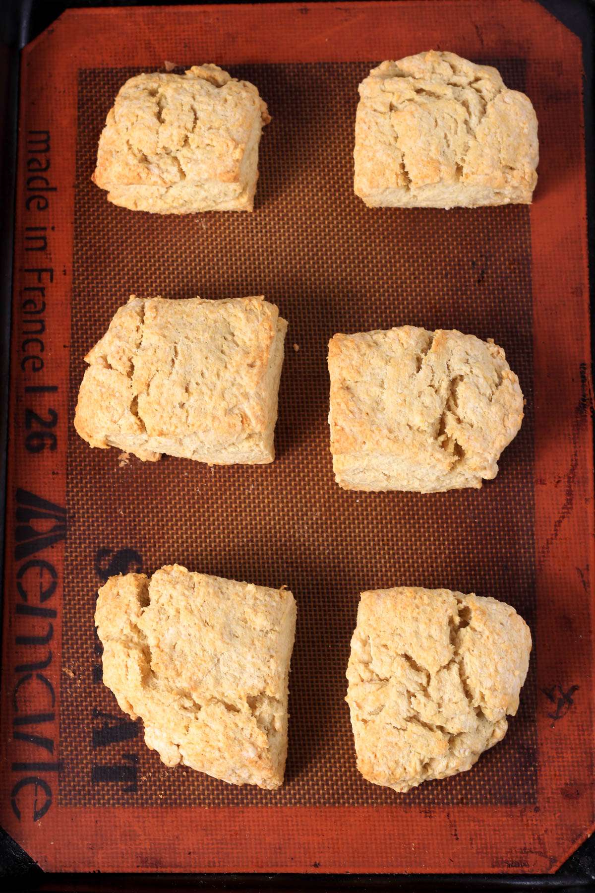Traditional buttermilk biscuits on a pastry mat lined baking sheet after baking.