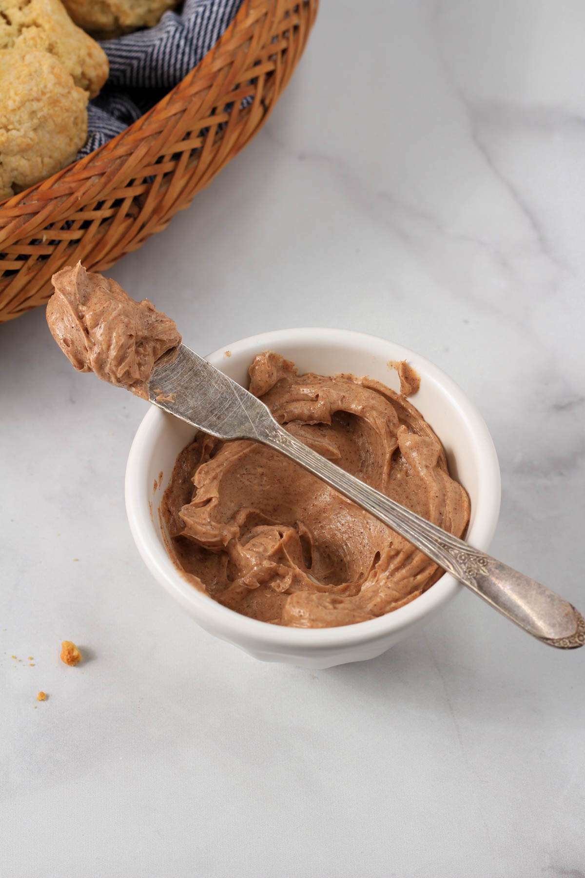 A white bowl with a silver butter knife on top with cinnamon honey butter.