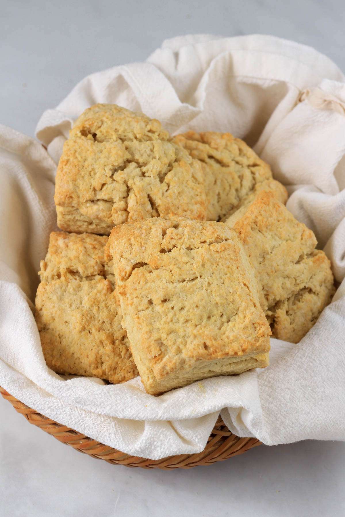 A white towel lined basket with traditional dairy-free buttermilk biscuits.