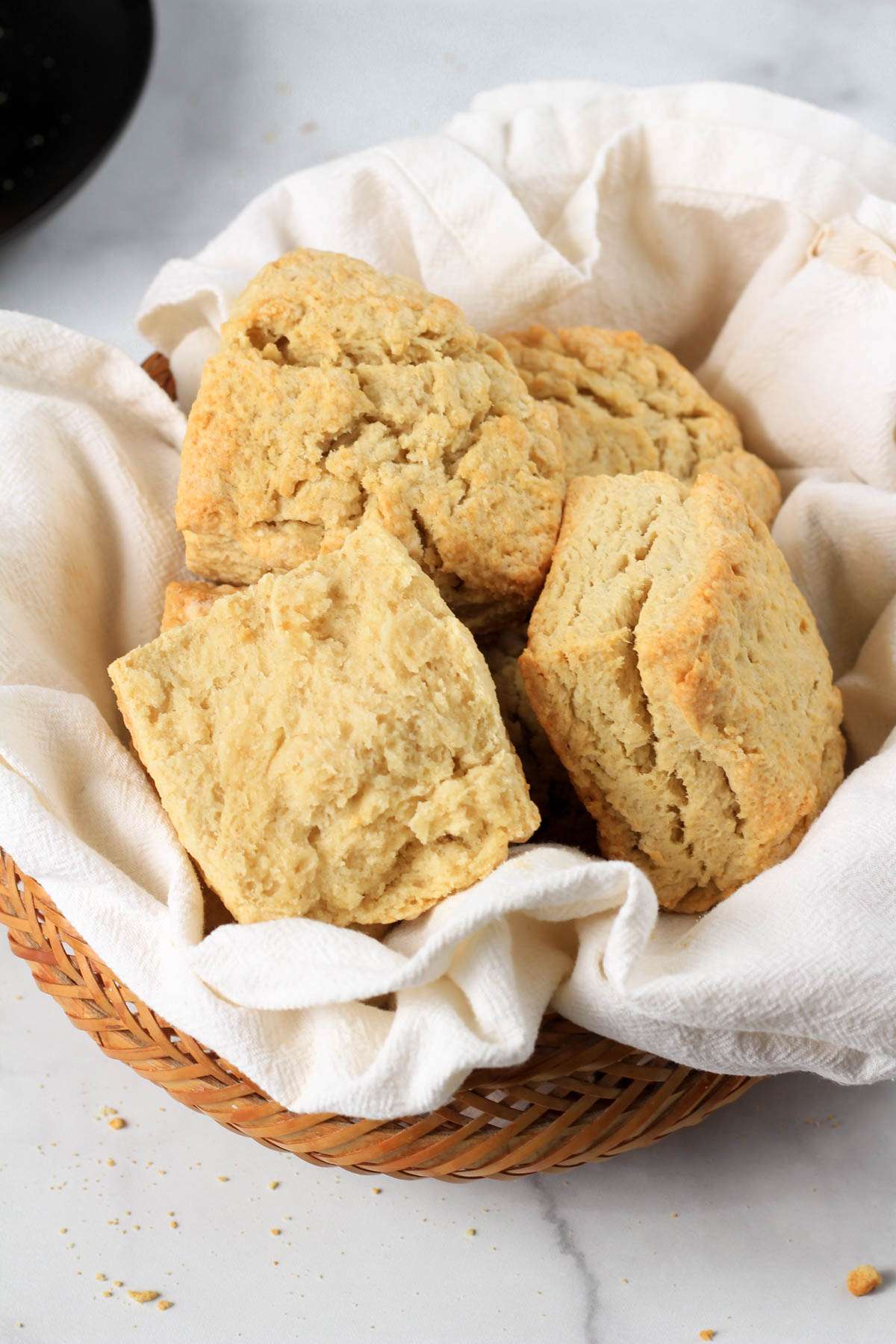 An open biscuit in a basket of buttermilk biscuits.