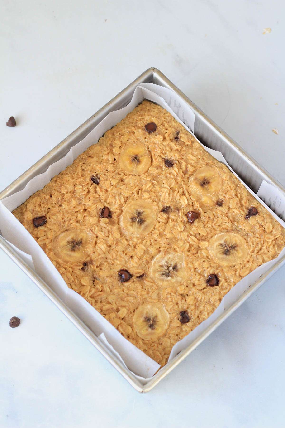 Banana baked oatmeal with chocolate chips in a parchment paper lined baking sheet after baking.