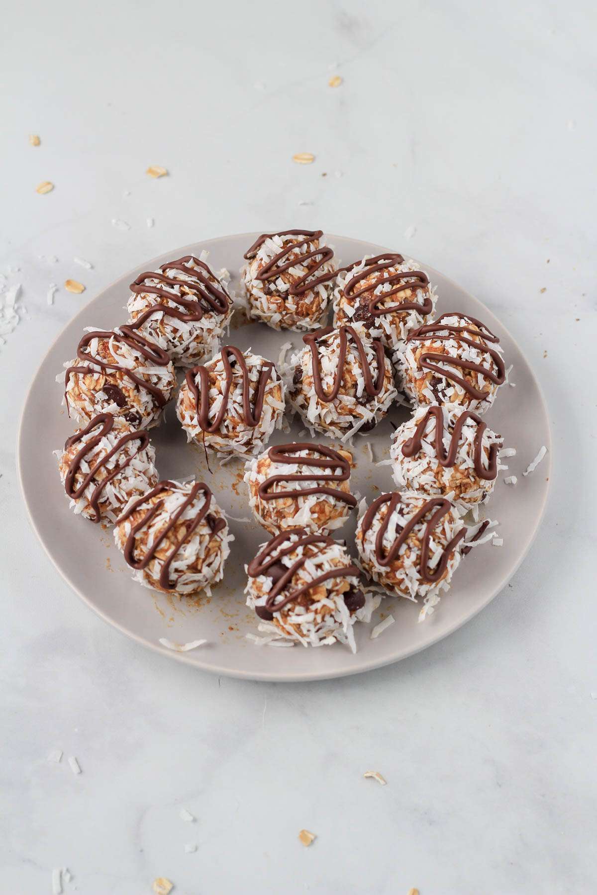 Almond joy lactation bites on a white plate topped with chocolate and shredded coconut.