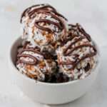 A bowl on a white counter with vegan almond joy lactation bites piled into the bowl.