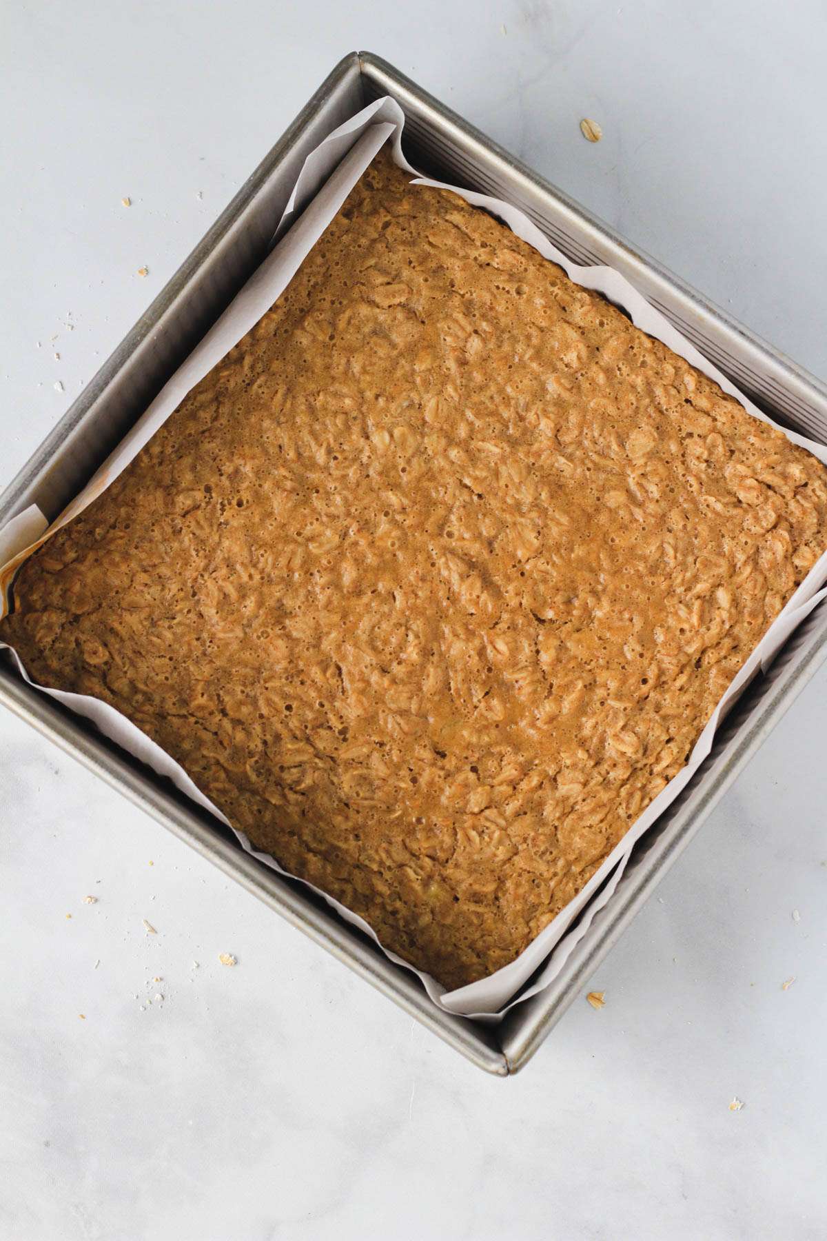 Peanut butter baked oatmeal in a parchment paper lined baking pan after baking.