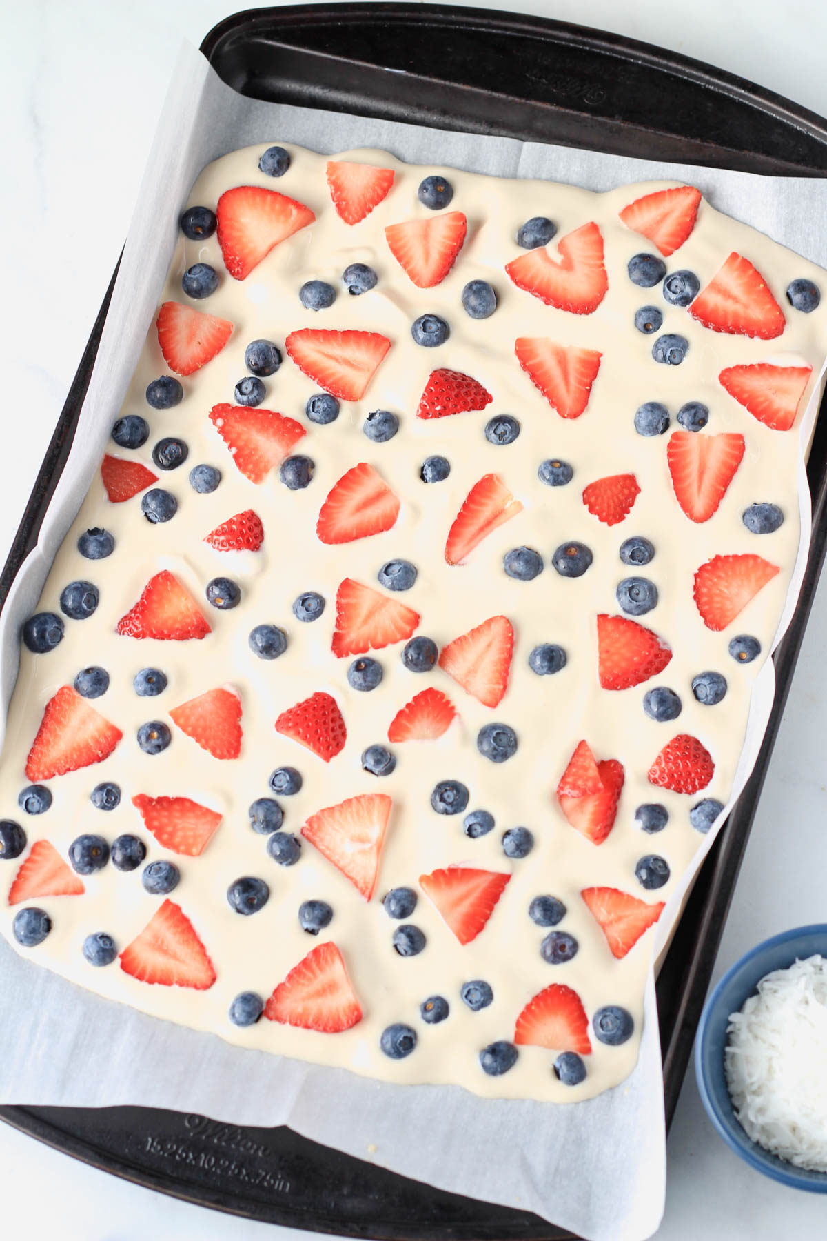 Yogurt on a parchment paper topped with strawberry and blueberry.