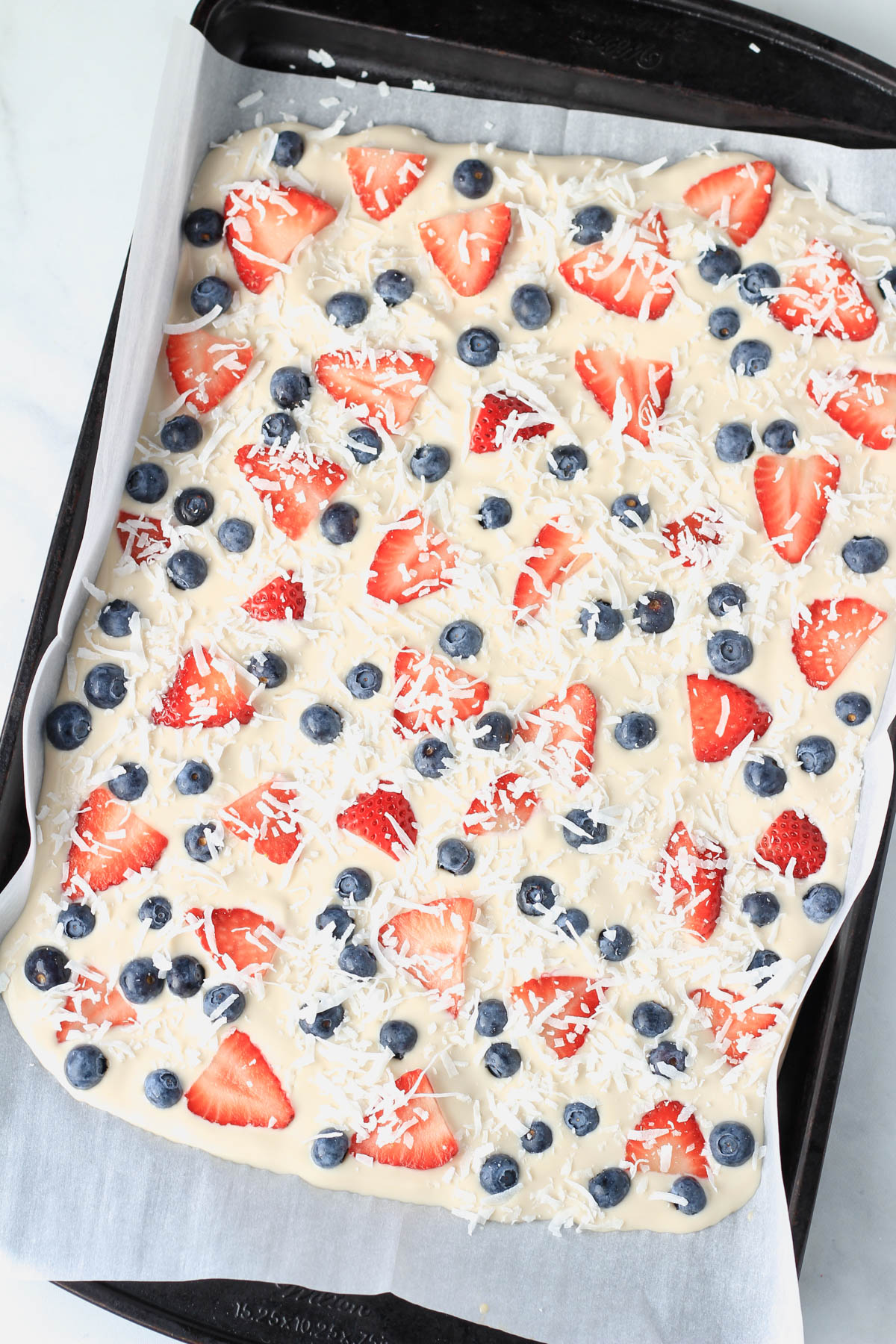 Vegan frozen yogurt bark on a parchment paper lined baking sheet before freezing.