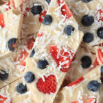 A slice of vegan frozen yogurt bark topped with fruit and shredded coconut.