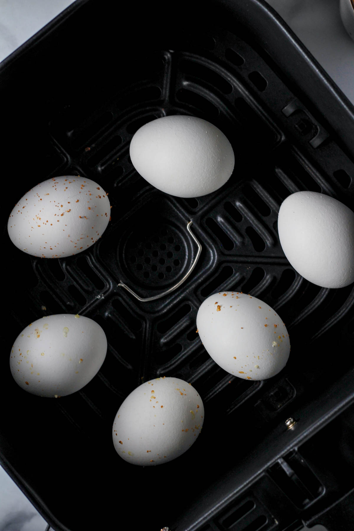 An air fryer basket with 6 eggs after they cook.