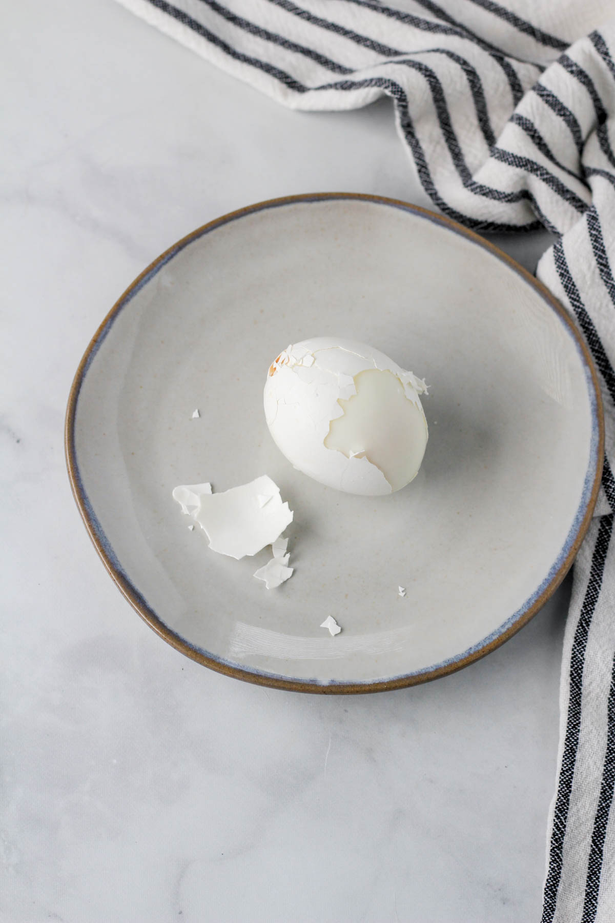 A small plate with one hard boiled egg after being cracked.