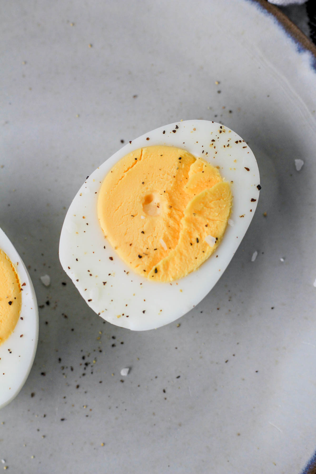A sliced hard boiled egg with salt and pepper.