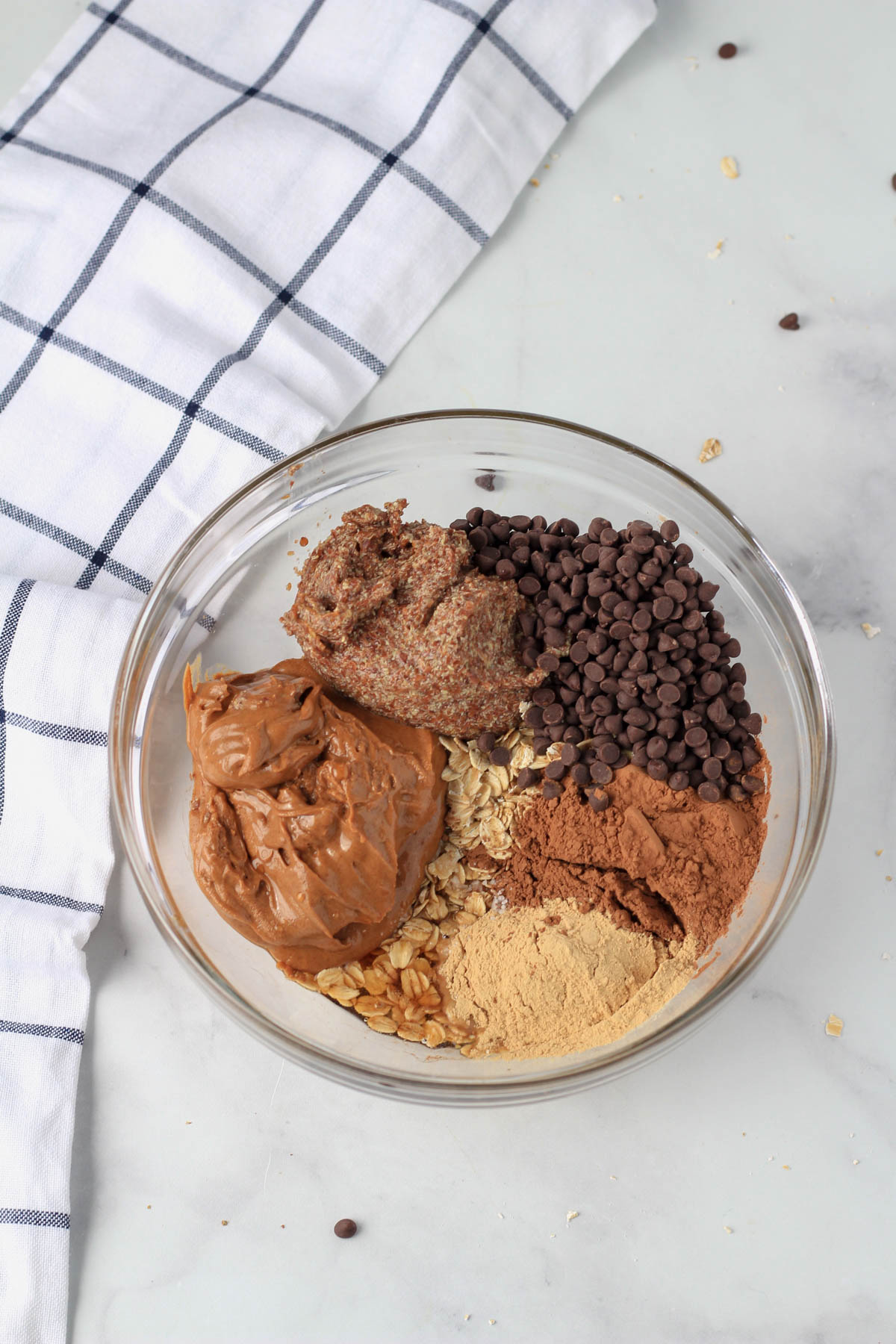 A glass mixing bowl with all of the ingredients for chocolate almond lactation bites before mixing.