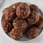A small white plate with vegan chocolate and almond butter lactation balls.