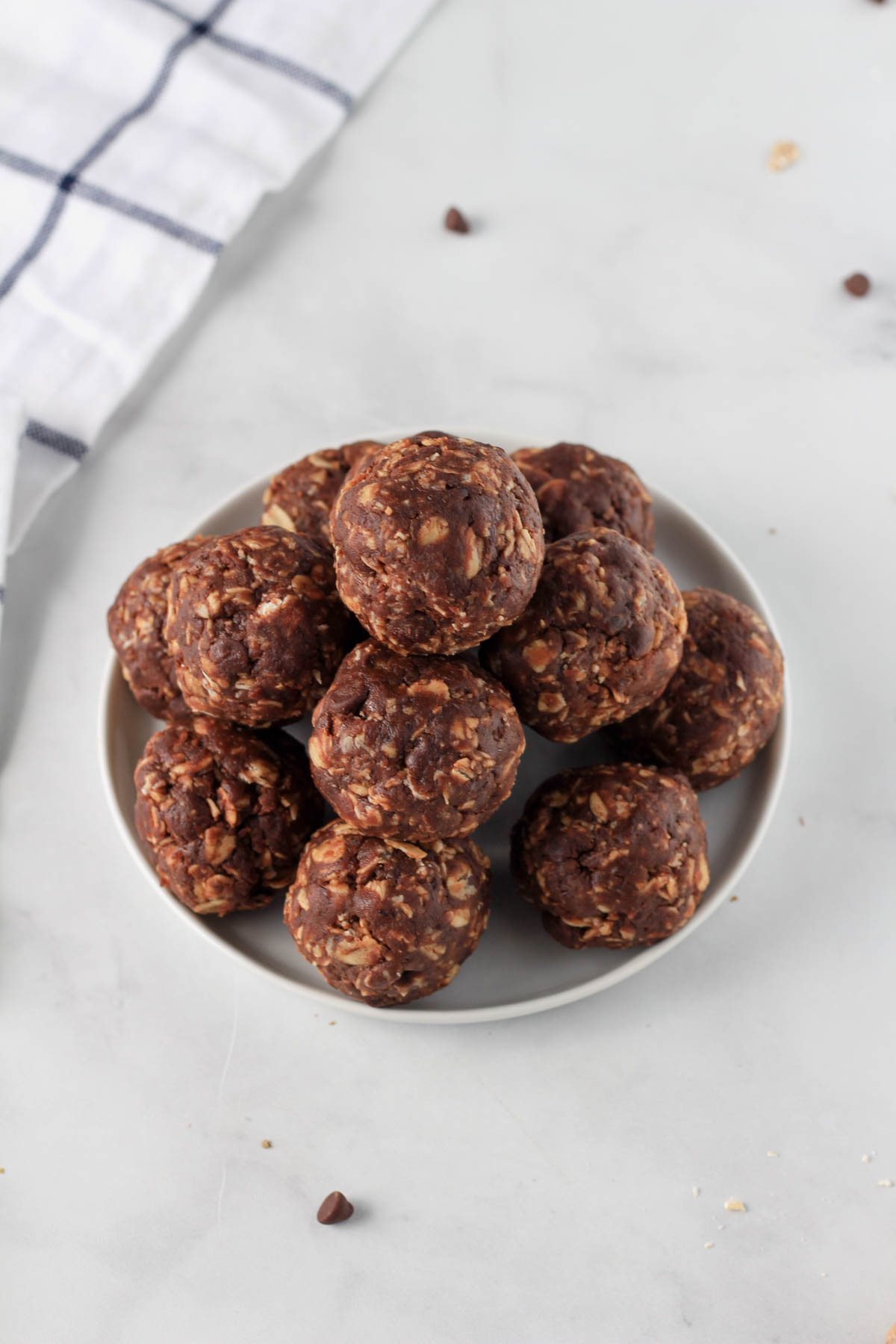 A small white plate of chocolate almond lactation bites on a white counter.