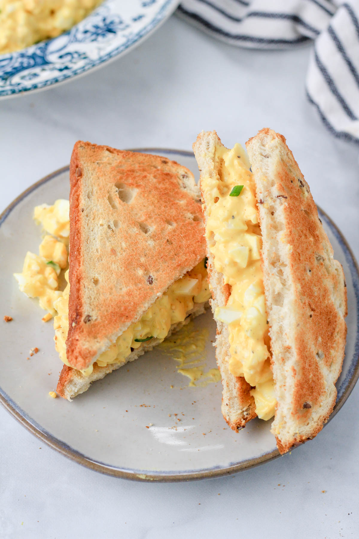 A classic egg salad sandwich sliced in triangles on toasted bread.