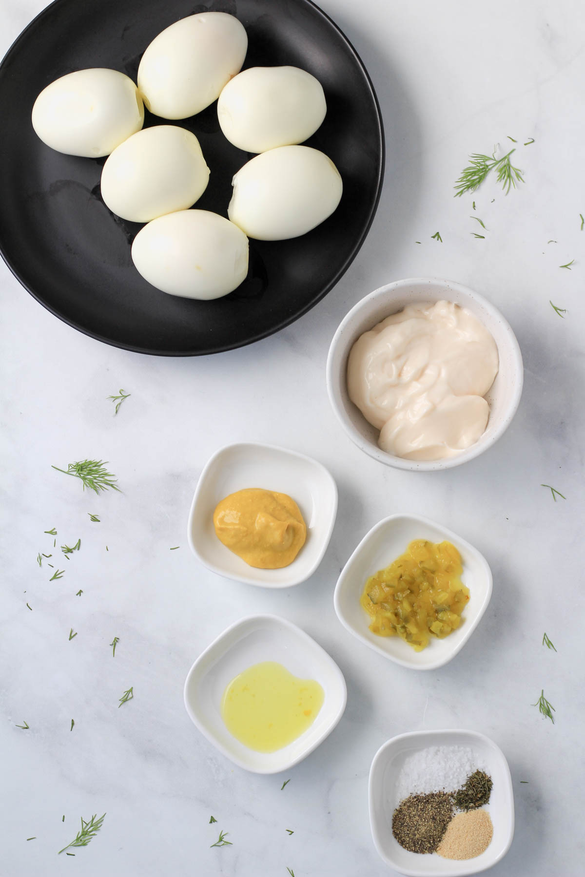 Ingredients for dill pickle deviled eggs on a white counter.