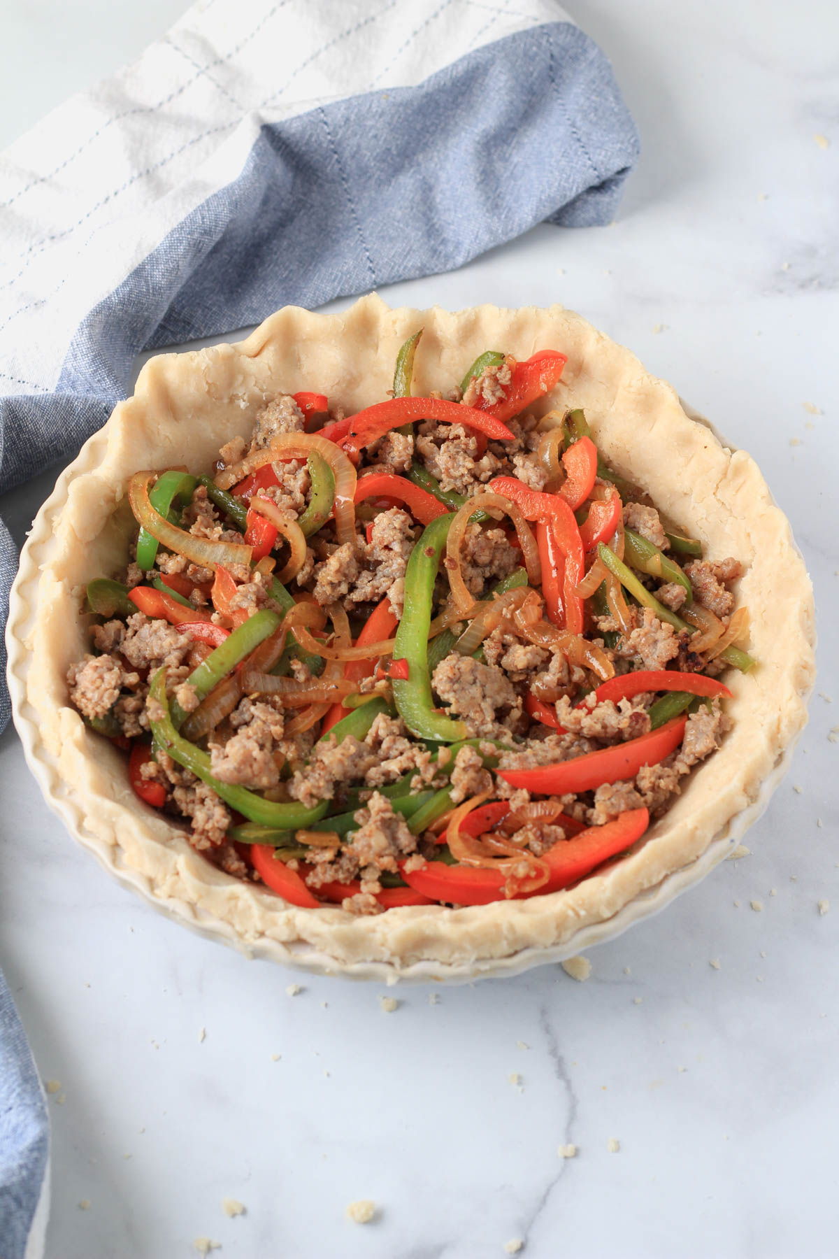 A pie crust filled with cooked sausage and bell pepper.