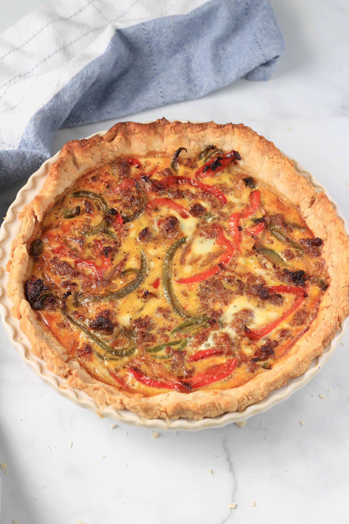 Sausage and bell pepper quiche on a white counter after baking.